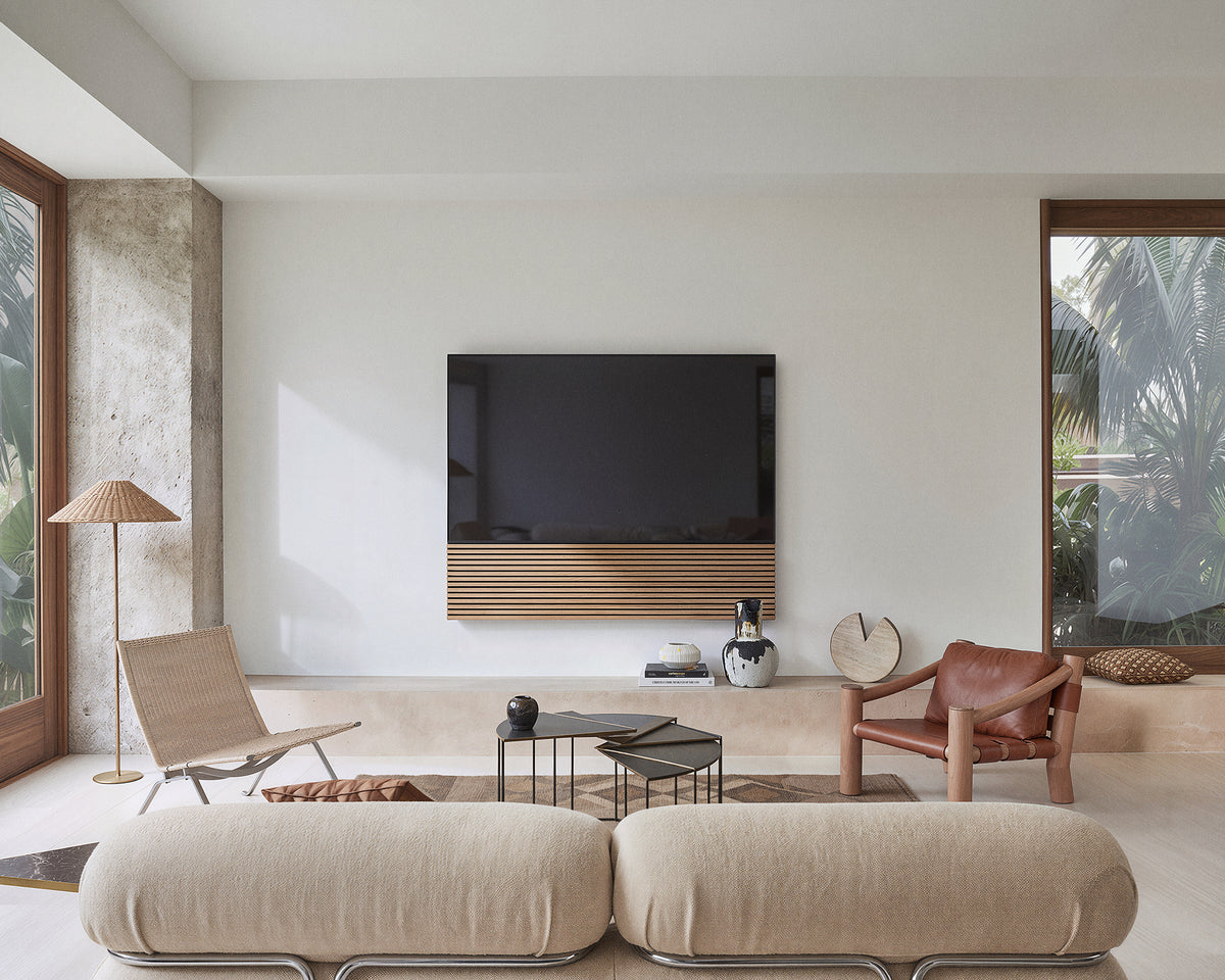 FITUEYES ZEN TM65 Grille TV mount above a coffee table in a living room with cream sofas and a lounge chair
