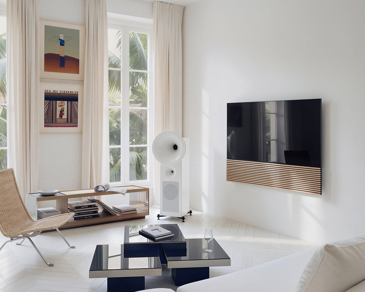 FITUEYES ZEN TM65 Grille TV mount in a bright listening room with white speakers and a glass coffee table