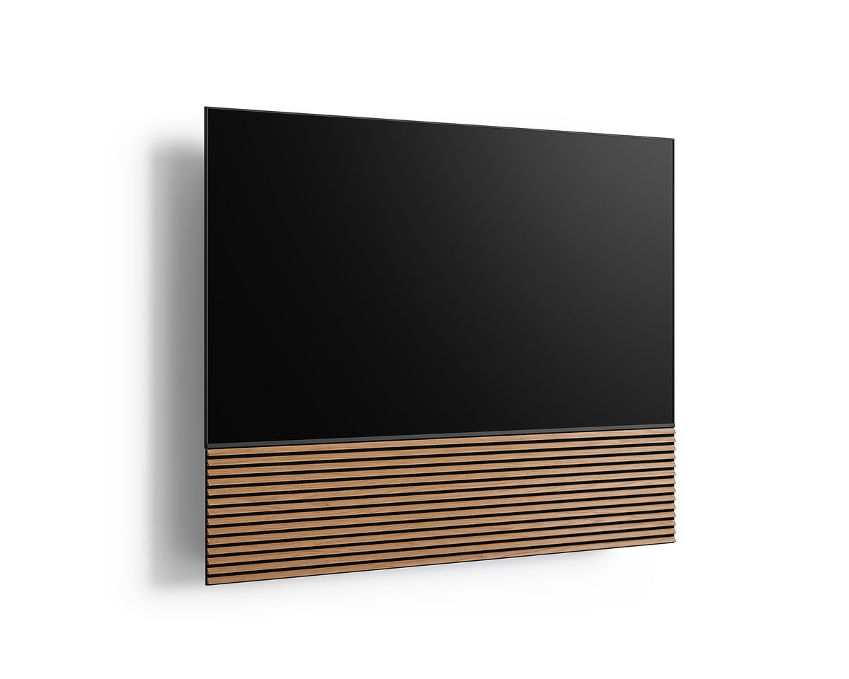 Angled front view of the FITUEYES ZEN TM65 Grille TV mount with a TV and wood-slat panel on a white background