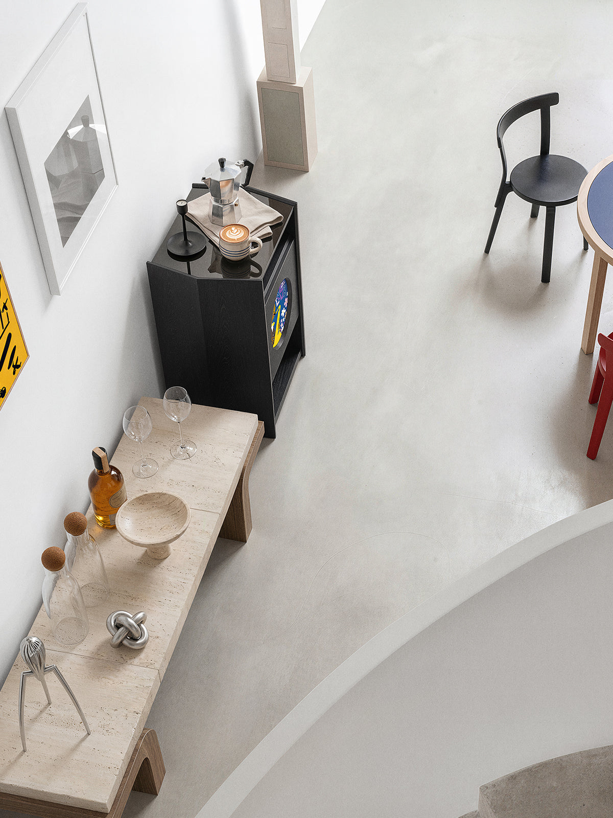 A Picasso stand next to a sculptural counter and colorful dining chairs