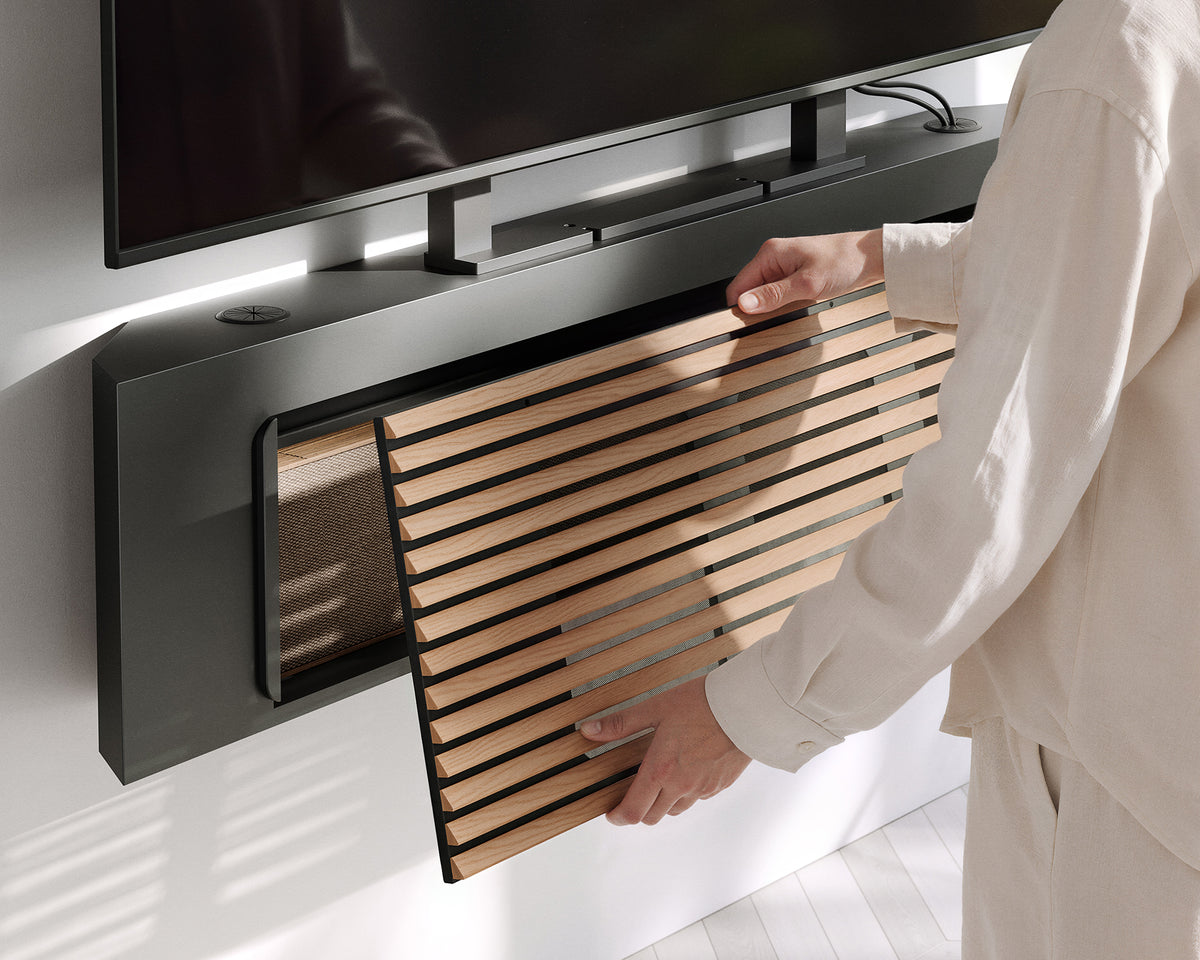 Person removing the wood-slat panel from the FITUEYES ZEN TM65 Grille TV mount to access the compartment beneath the TV
