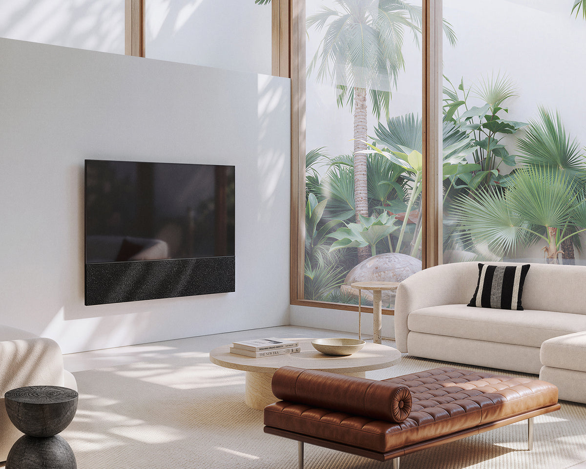 FITUEYES ZEN TM75 Fabric TV mount on a living room wall beside a sofa, woven coffee table and large window