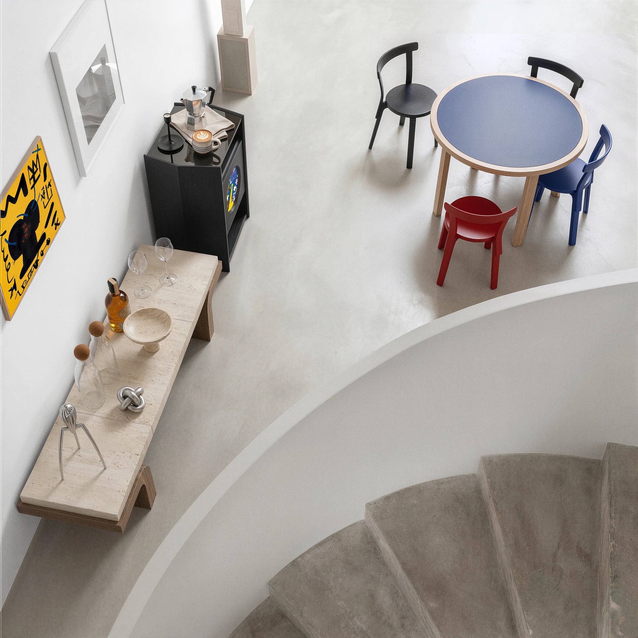 A Picasso stand next to a sculptural counter and colorful dining chairs
